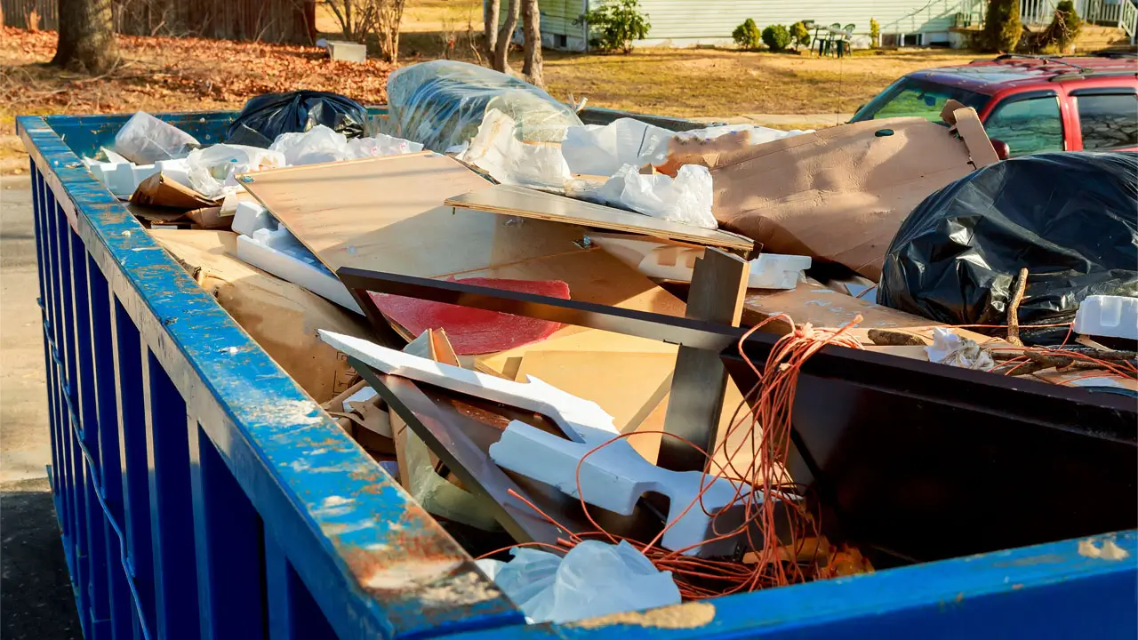 blue dumpster filled with various discarded items, showcasing a mix of waste materials.