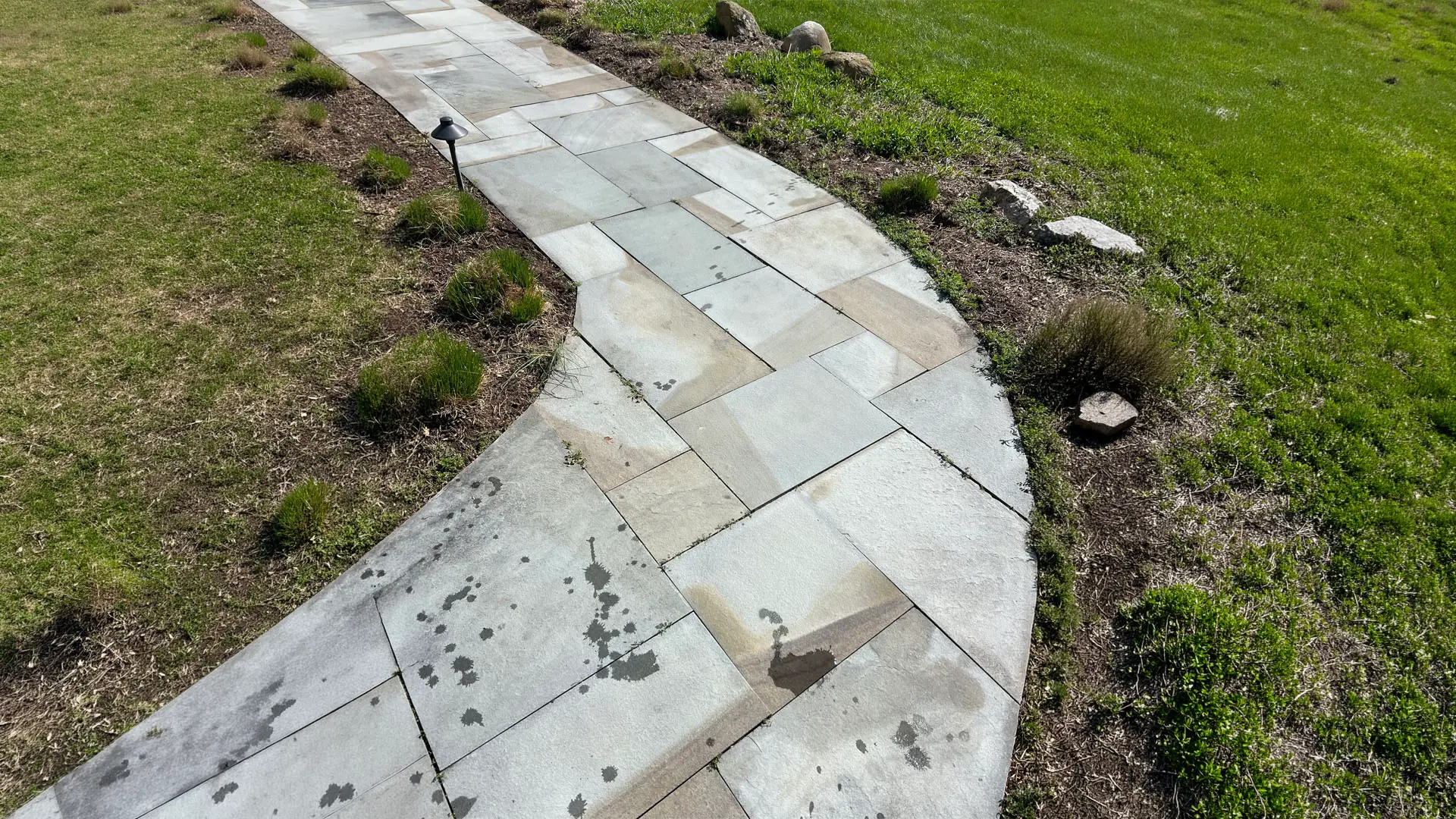 A stone walkway meanders through a lush green grassy area, inviting visitors to explore the surroundings.