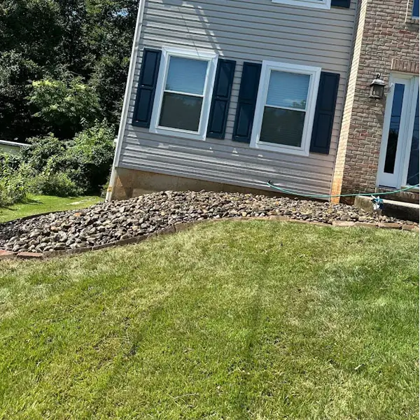 A well-maintained lawn featuring grass and decorative rocks in front of a residential house.